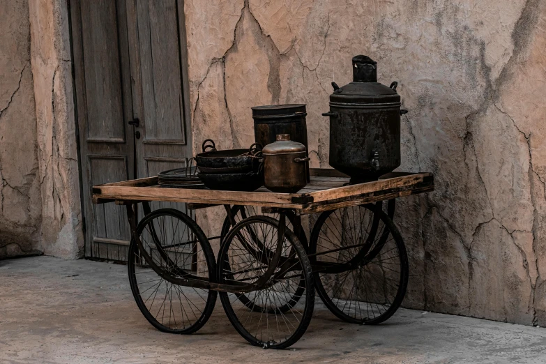 an antique bike in front of an old door with an iron table that is holding items