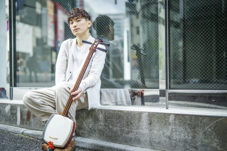 the young man sits on the steps while holding his music instrument