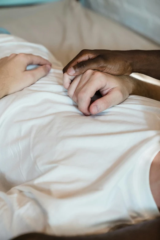 a man holding the hand of someone who is laying in bed