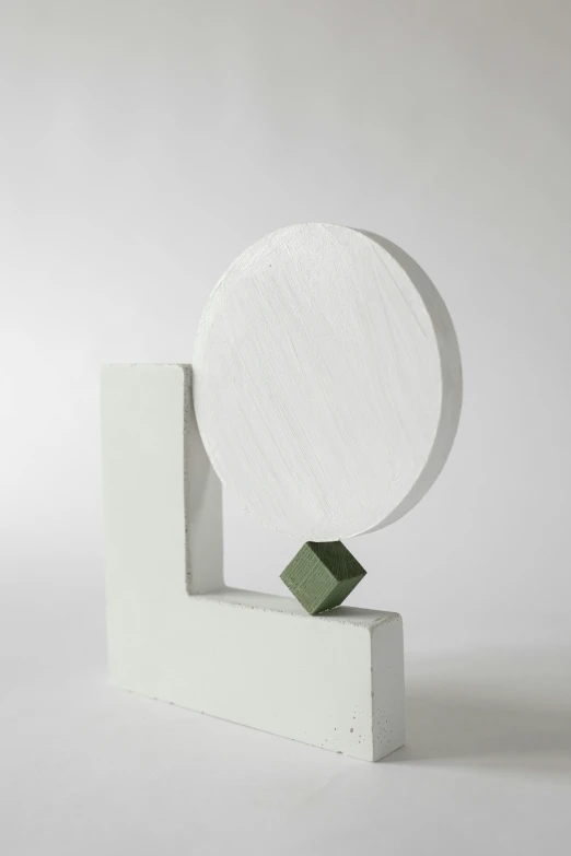 a small white sculpture has green geometric shapes