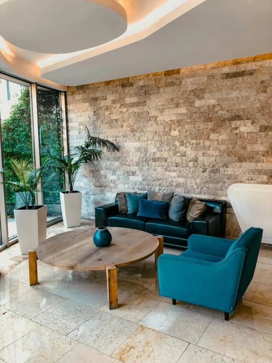 a living room with blue chairs and a stone wall