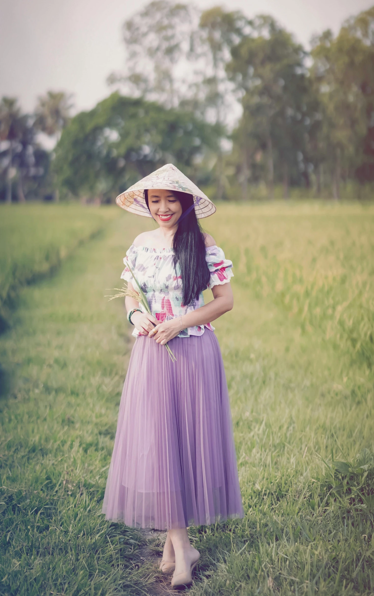 a woman standing on a field wearing a hat