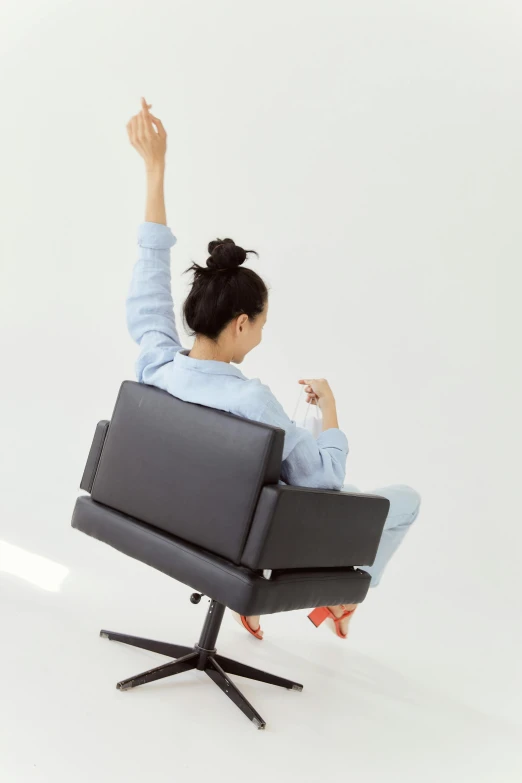 a woman sitting in an easy chair raising her arms in the air