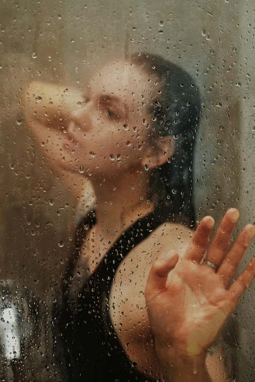 a woman taking a po out of a rainy window