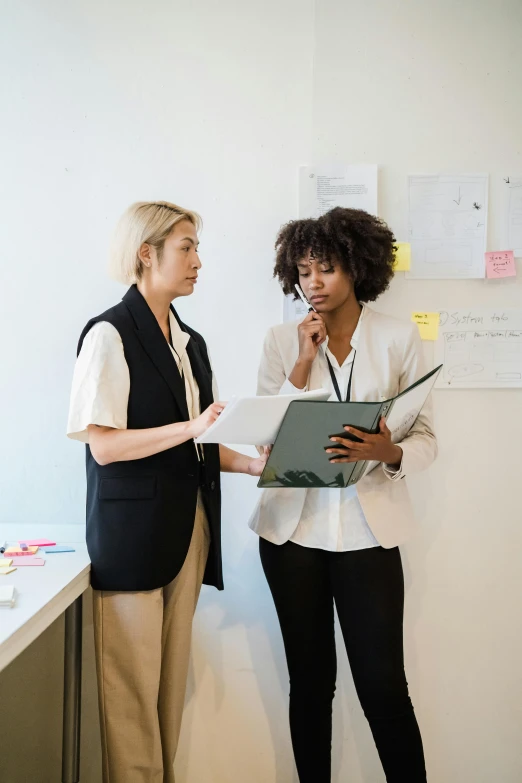 two women wearing black and white standing next to each other in an office