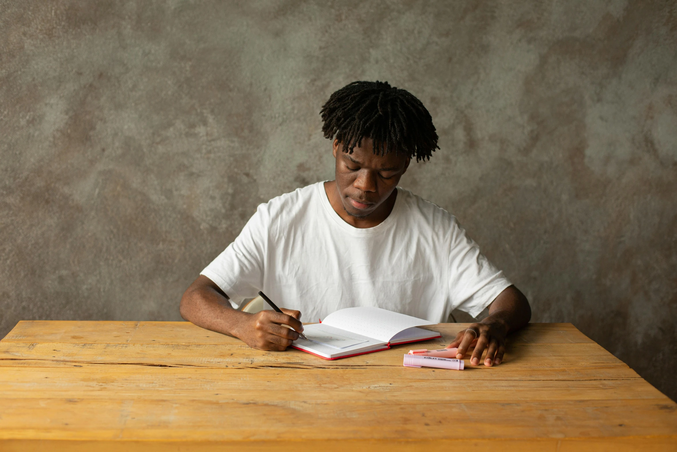 a man sitting at a table while writing in a book