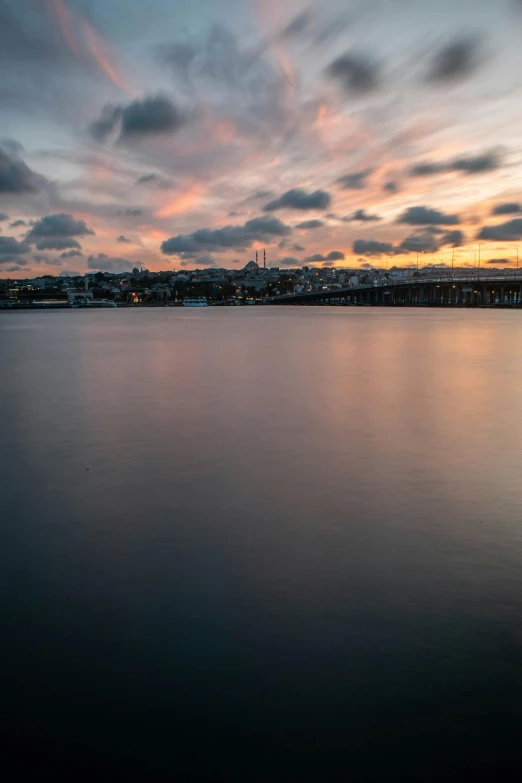 the sky is setting over a lake near the dock