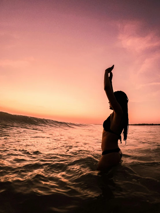 a woman holding a kite above the water in a body of water