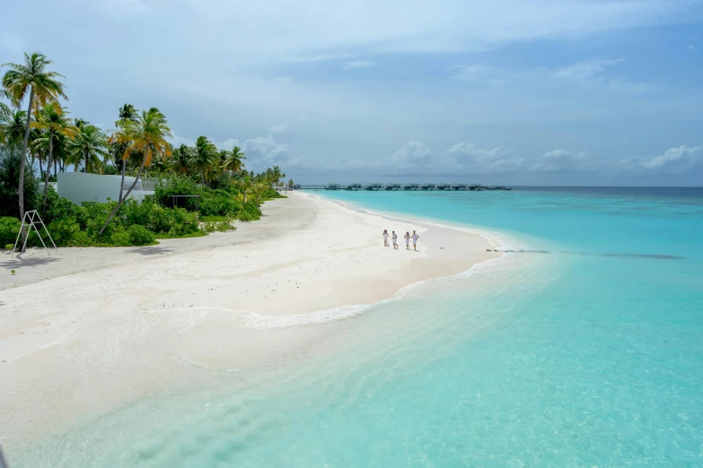 four people walking on the shore of an island