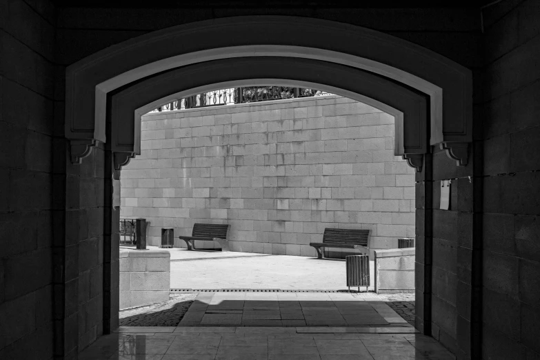 a large archway leads to a sidewalk with several benches in the center