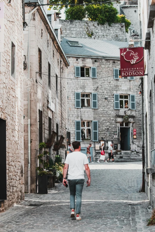 a man in white shirt walking down a stone street