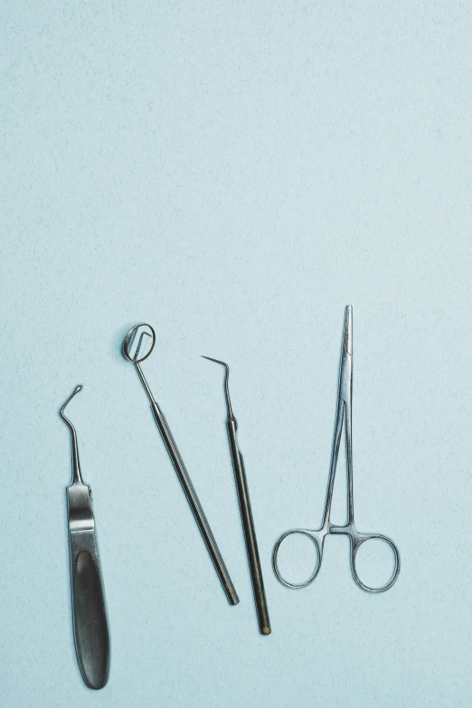 three pairs of surgical instruments are sitting on a light blue background