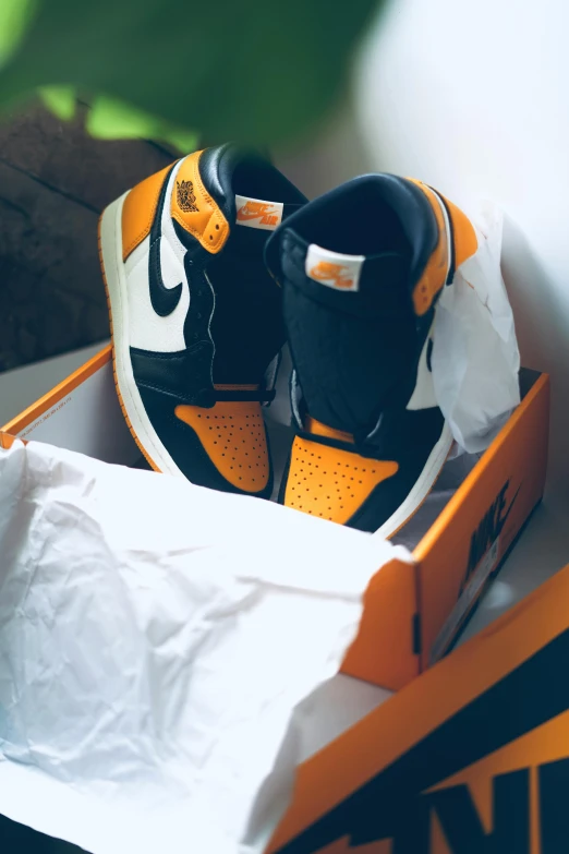 a pair of black and yellow sneakers in an open box