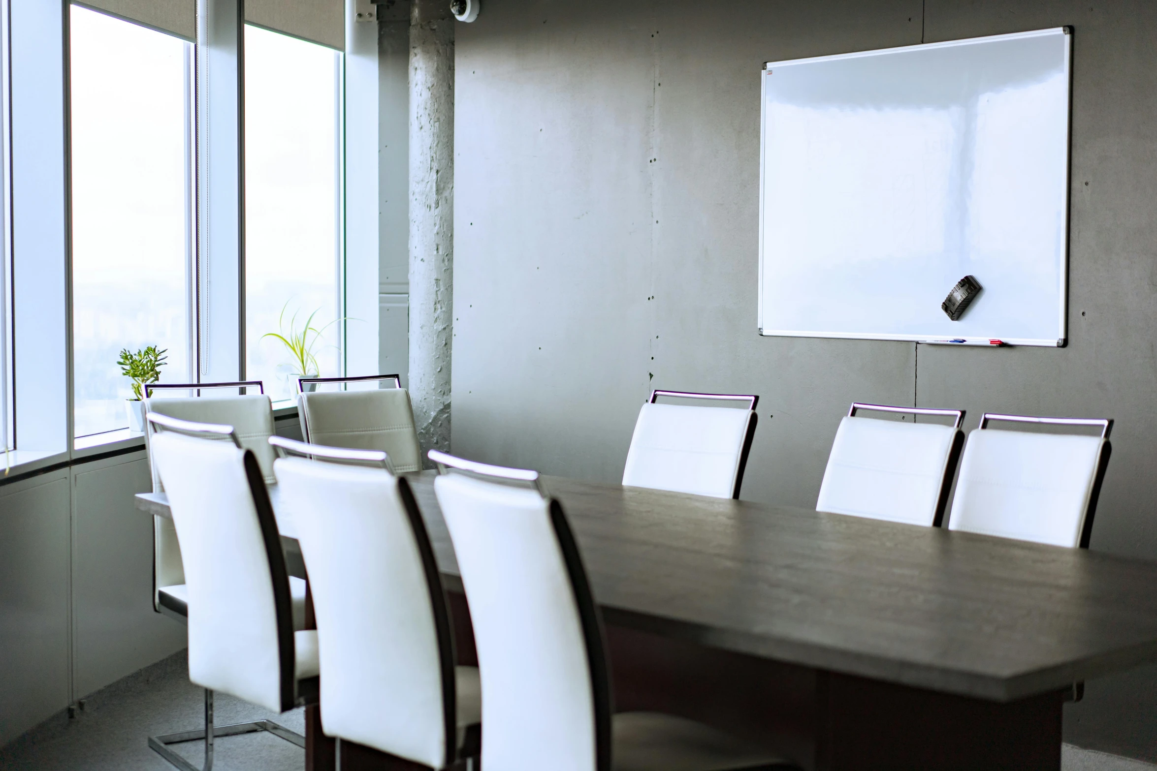 a conference table with several white chairs in front of the board