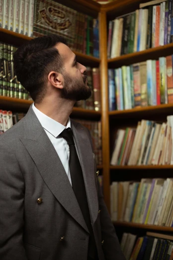 man in suit looking at bookshelves