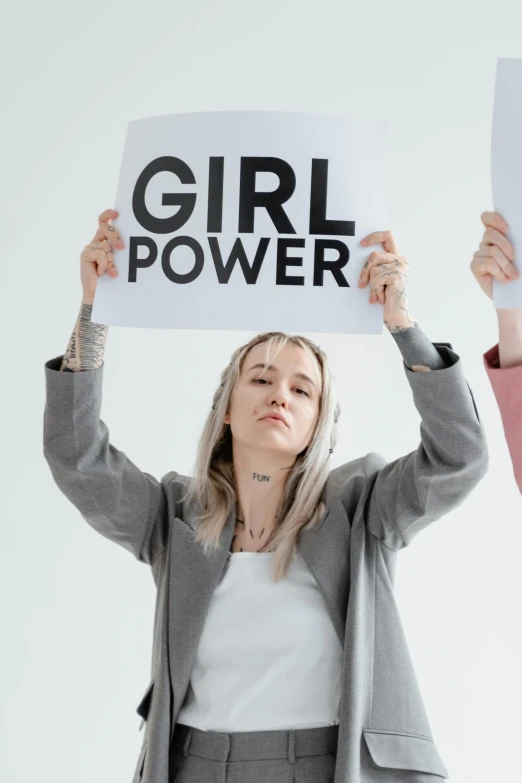a girl holding a paper reading girl power in both hands