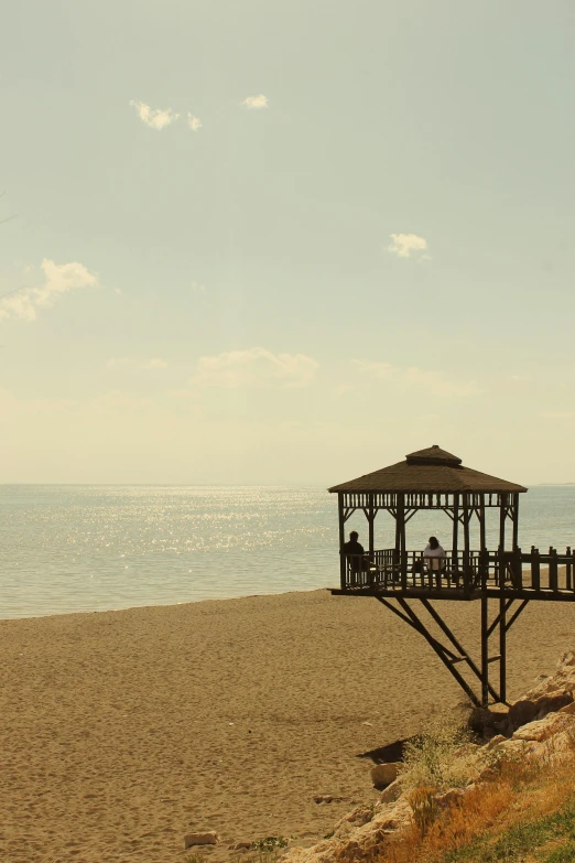 an outdoor structure on a beach with the ocean in the background