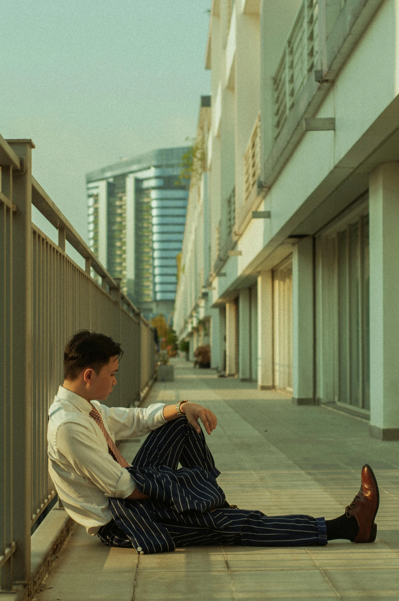 the young man is sitting on a railing outside