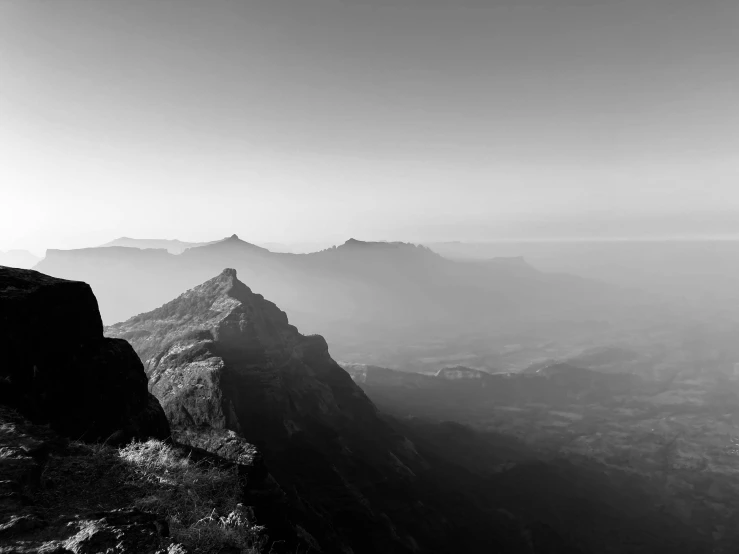 a man in hiking gear stands at the edge of a rocky cliff