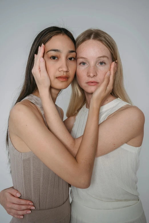 two s posing for a pograph with one holding her hand near her face