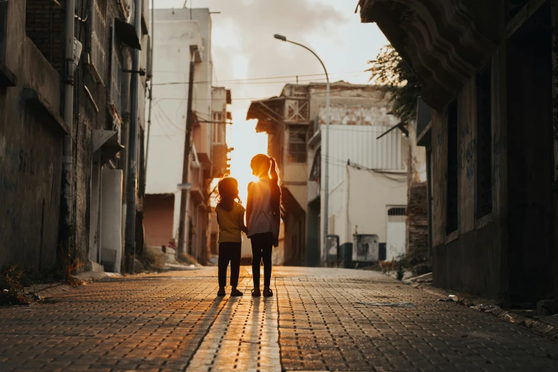 two people are walking down the street, one is holding a red umbrella