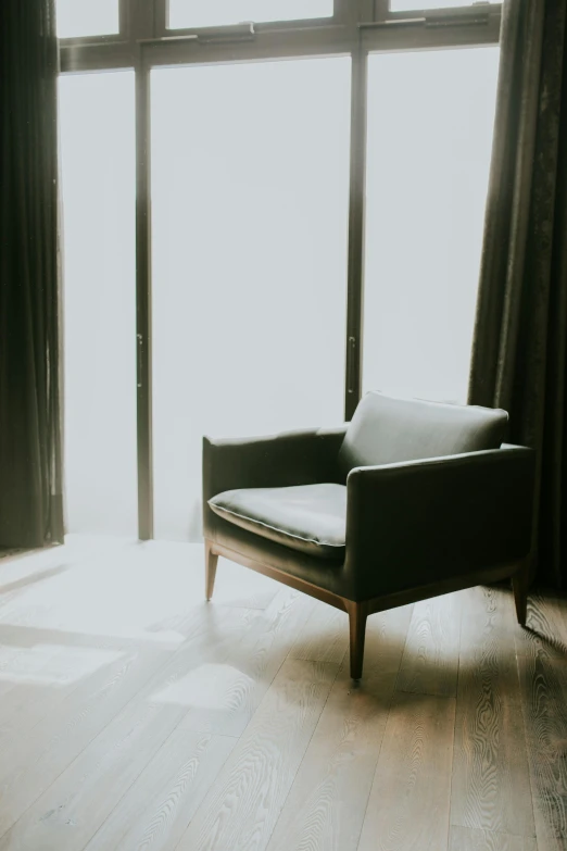 a chair sits in a sunny room with two windows