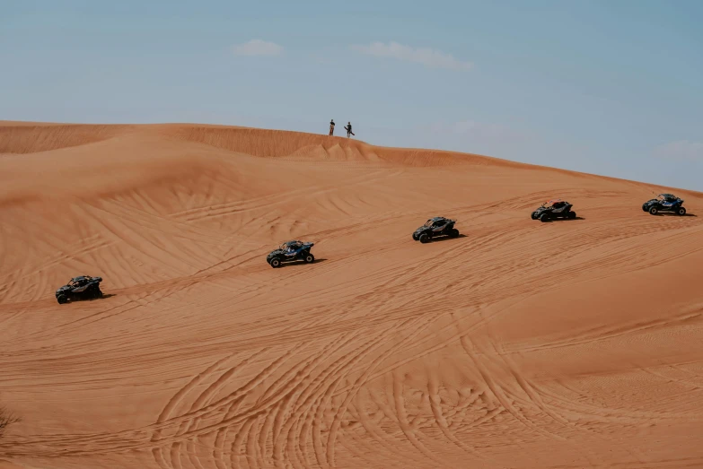 four cars on desert sand during daytime time