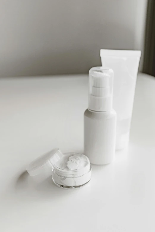 white cosmetic products including facial cream and an empty bottle