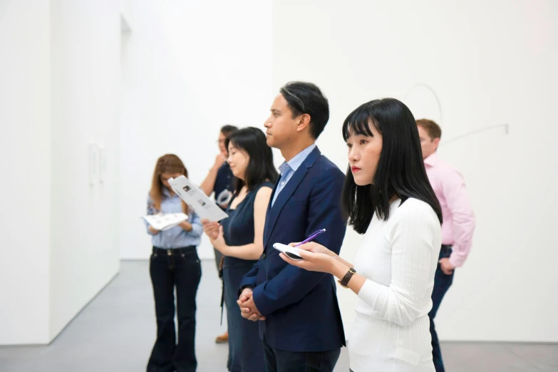 several people standing next to each other in an art gallery