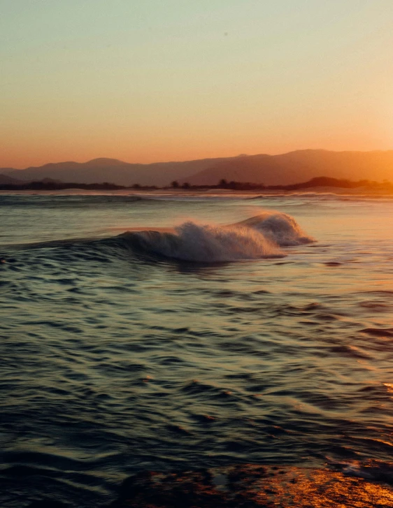 a sunset and ocean with small waves rolling in