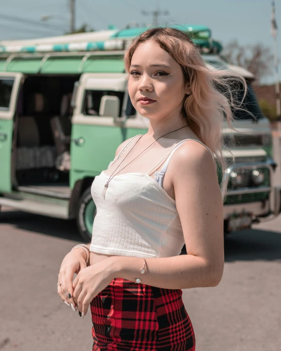 a woman standing next to a green and white bus