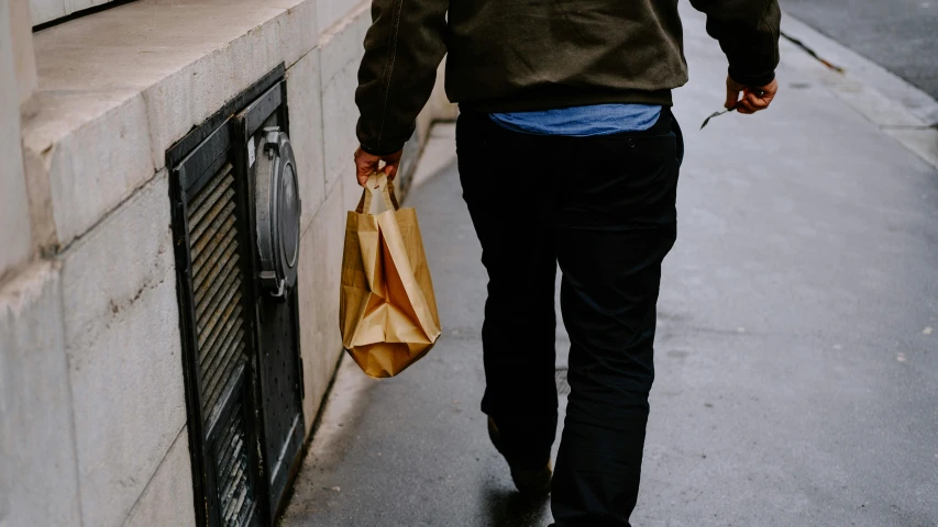 a man is walking down the street while carrying some bags