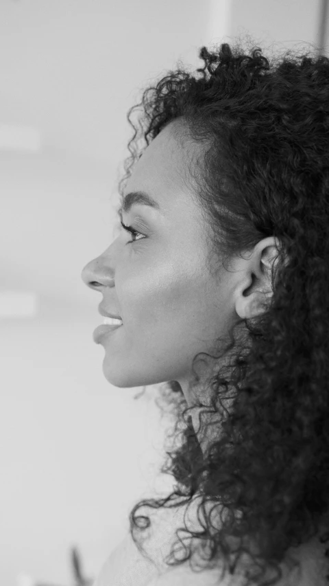 a woman with curly hair smiling into the distance