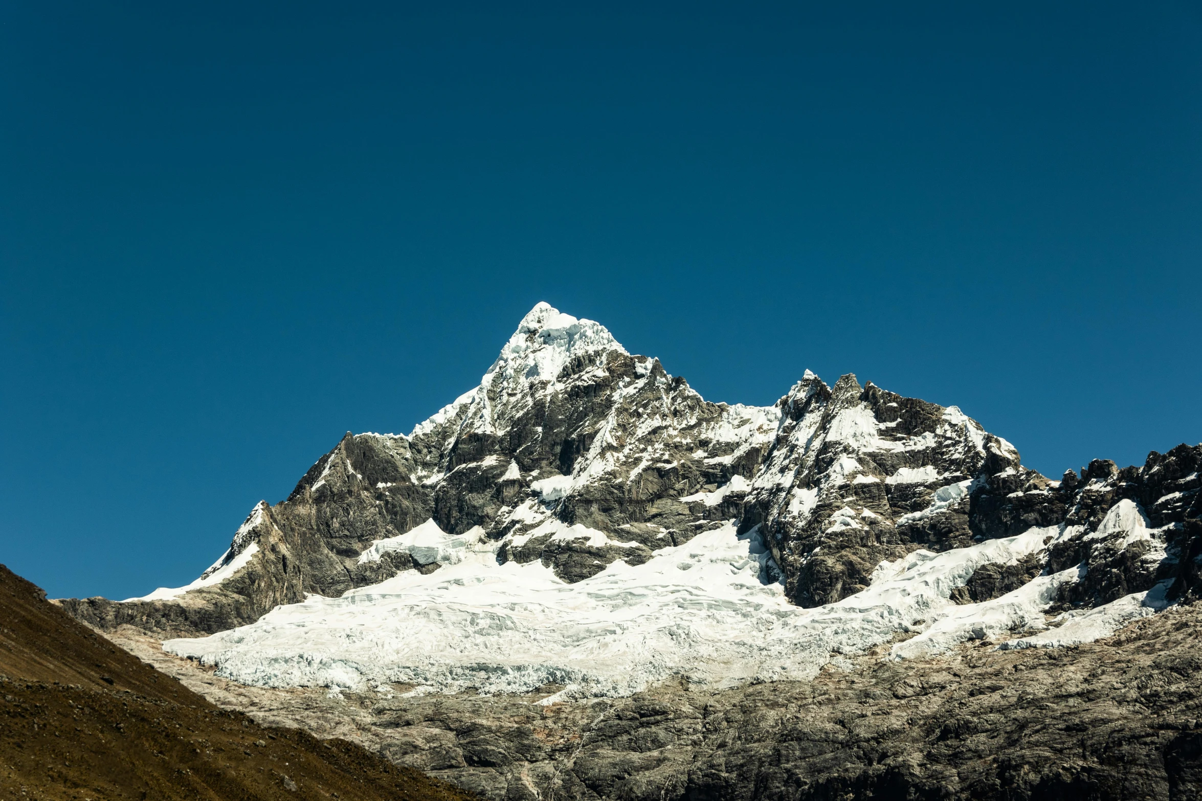 a mountain that is covered in snow next to a river