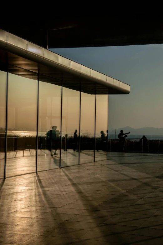 a glass wall with some people sitting at the end of it