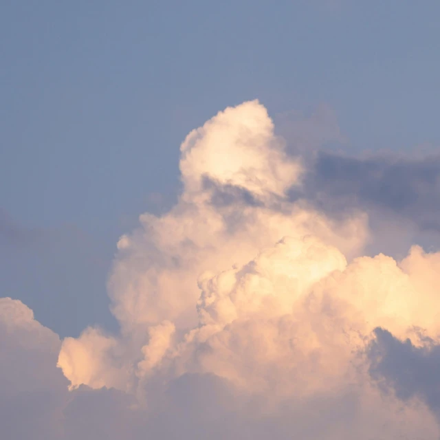 a plane flying up in a cloudy blue sky