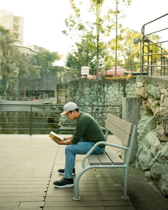 a man sits on a bench reading in the shade