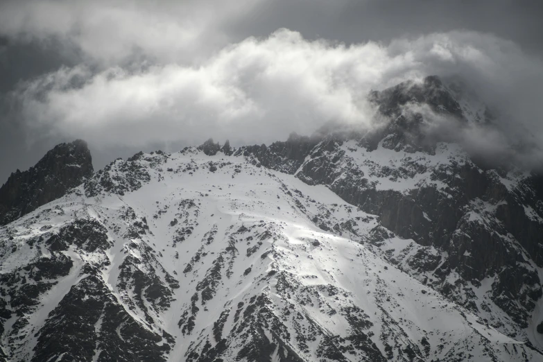 a mountain covered in snow under a cloudy sky