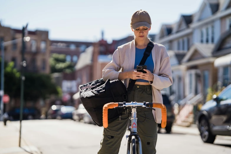 there is a woman that is riding her bike looking at her cell phone