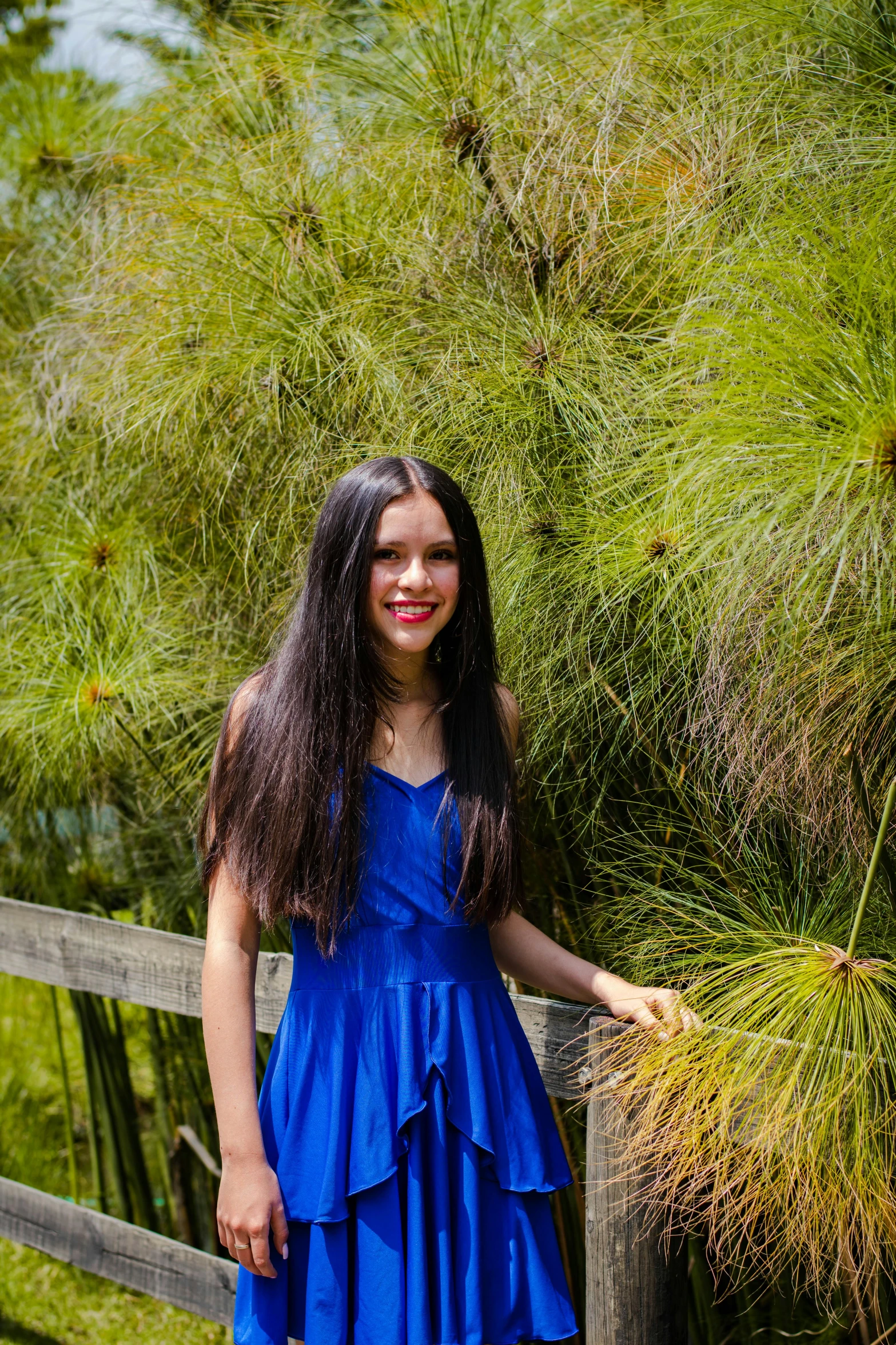 a young woman is posing in front of some trees