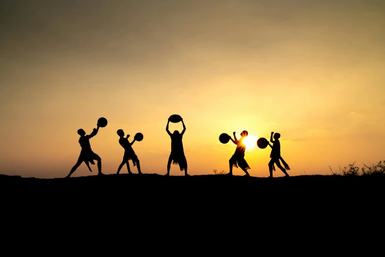 silhouette of people playing basketball at sunset