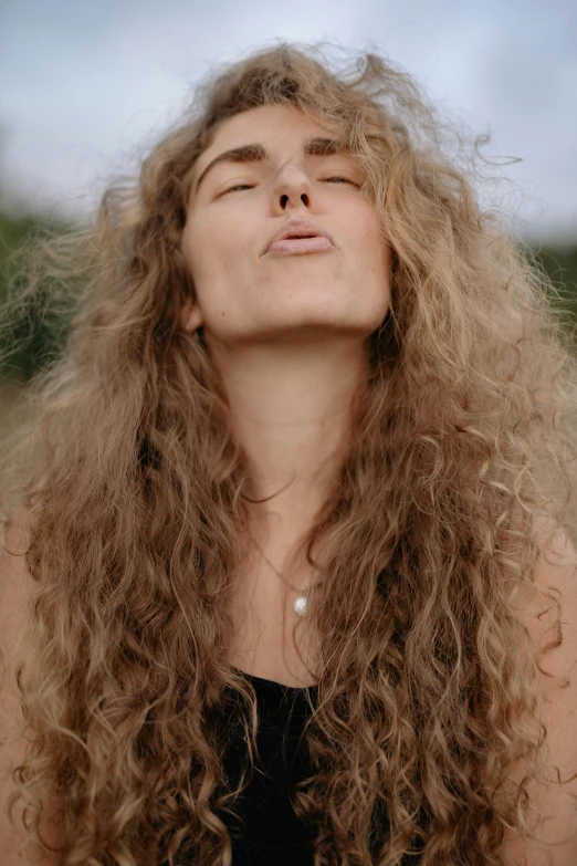 a woman with long curly hair is looking up