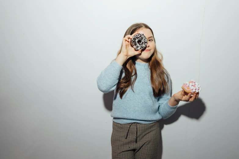 girl in blue sweater looking through donut holes