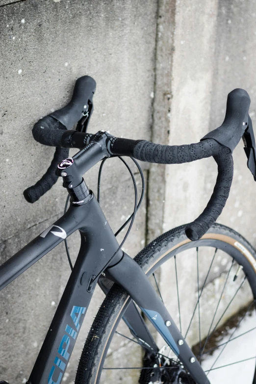 the handlebars on a black bike against a gray wall