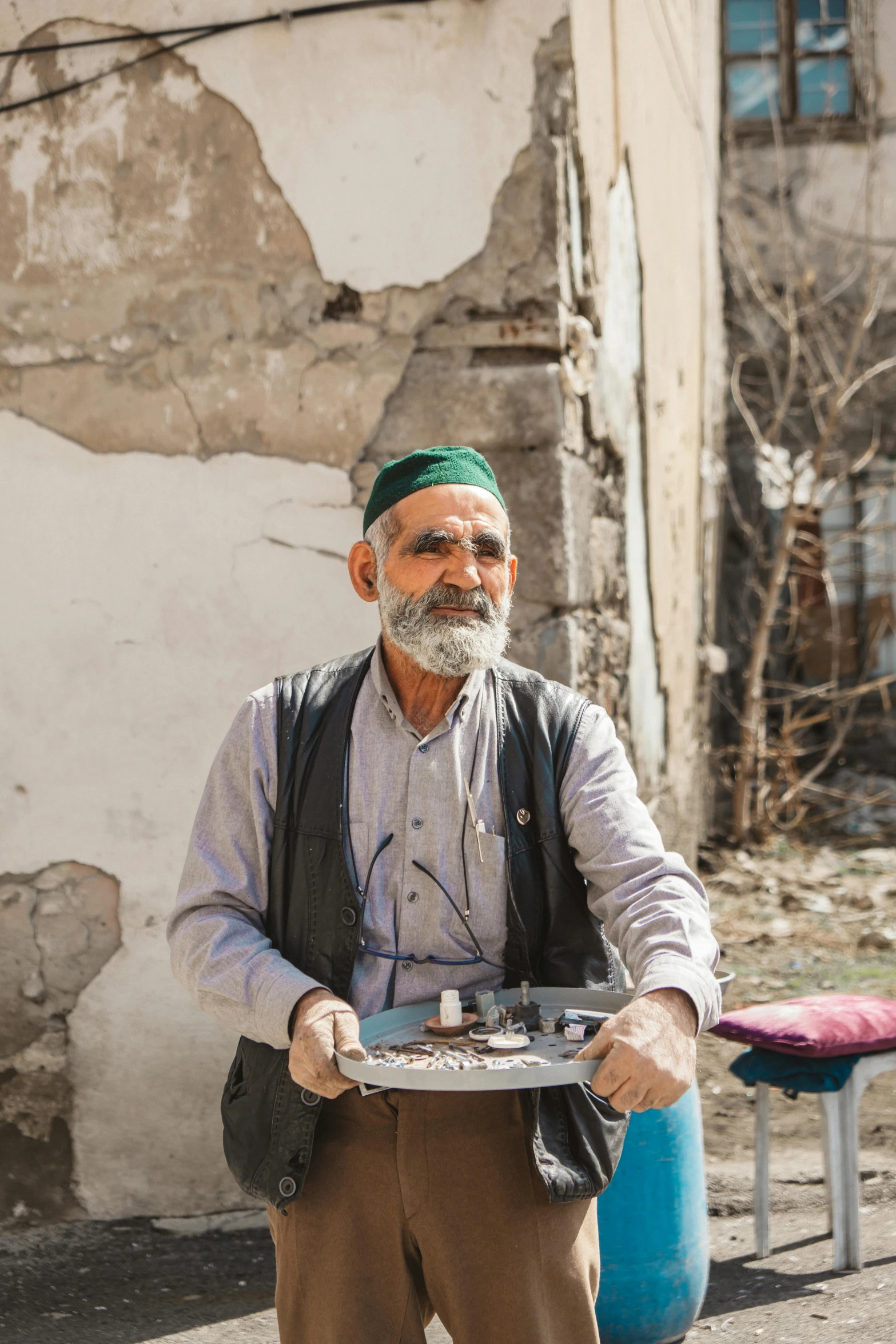 an old man standing next to his home carrying a plate