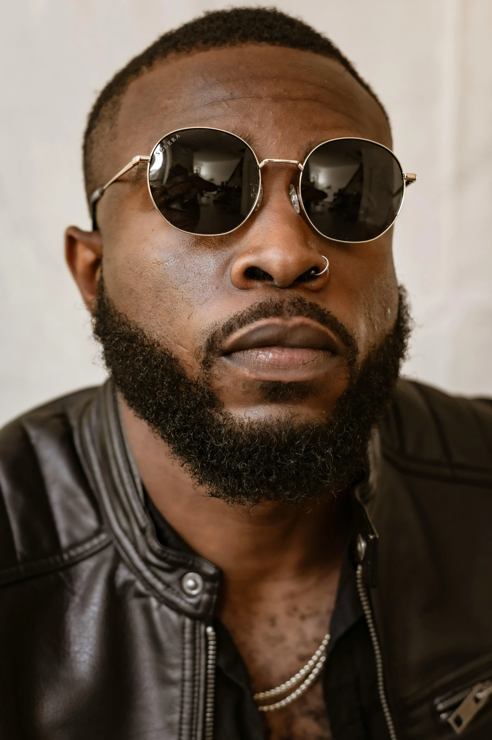 a man in leather jacket and shades looking at the camera