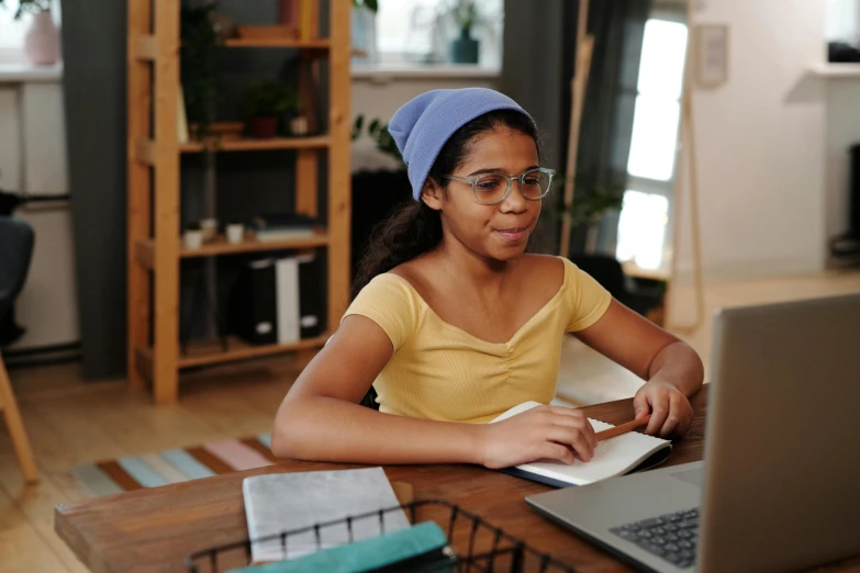 an african girl with a hat on her head using a laptop computer