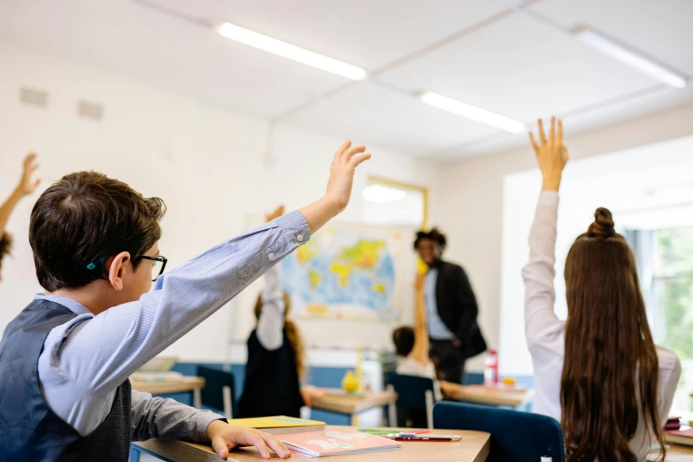 children in the classroom raising their hands to answer questions