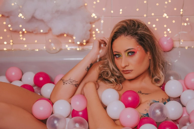 a woman sits in the bathtub with a lot of balloons