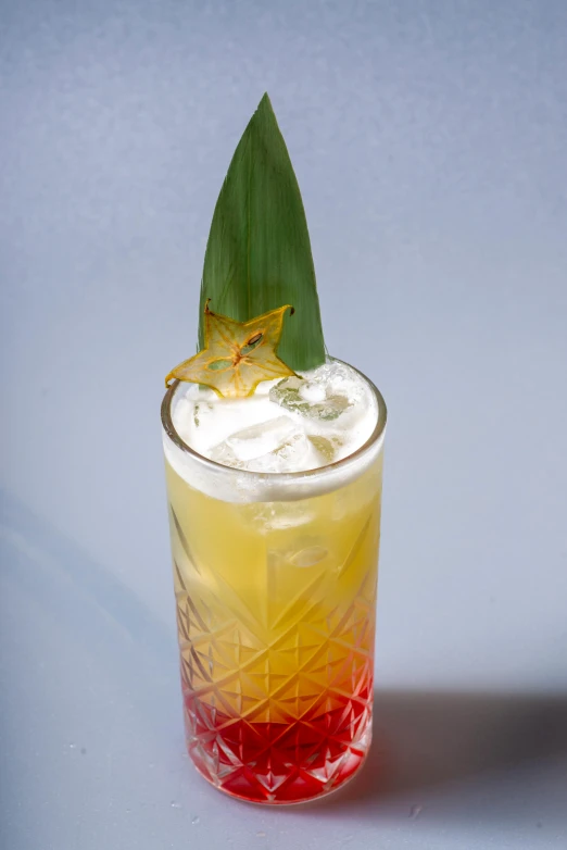 the drink in the glass is decorated with an orange flower and a leaf